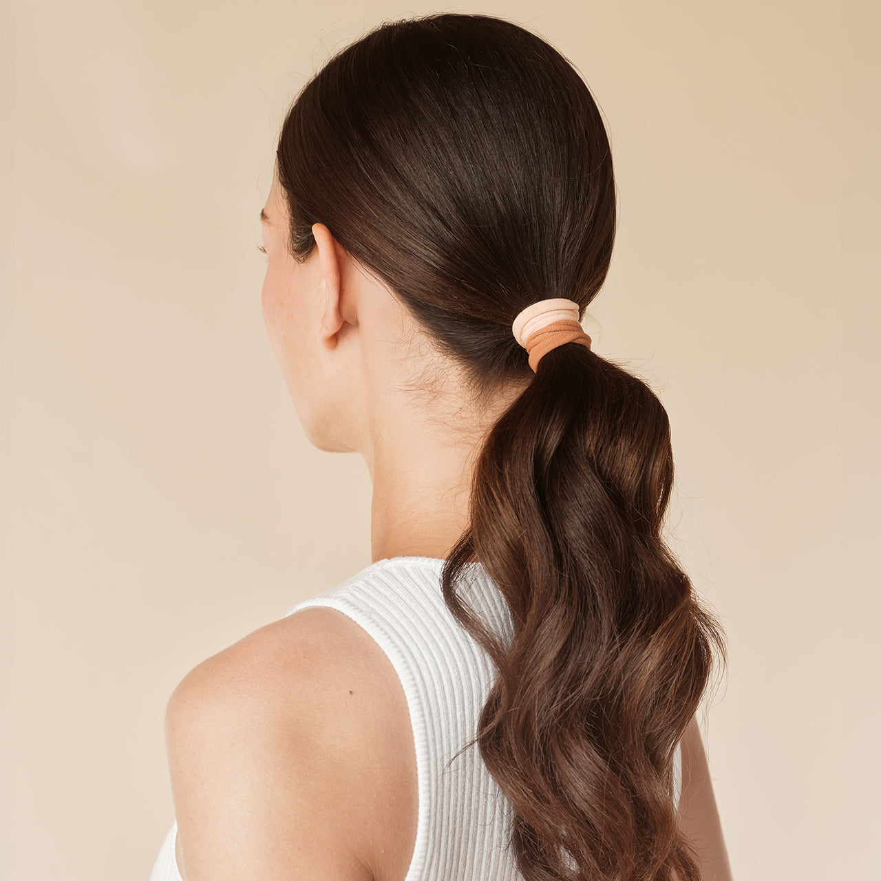 KITSCH Blush Elastic Hair Ties 20pc Set — model styling ponytail with blush elastic — Every ponytail's perfect hair basic & eco-friendly too — kind on your hair and the environment